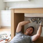 Bricoleur installant le robinet sous un évier inox avant pose dans le plan de travail
